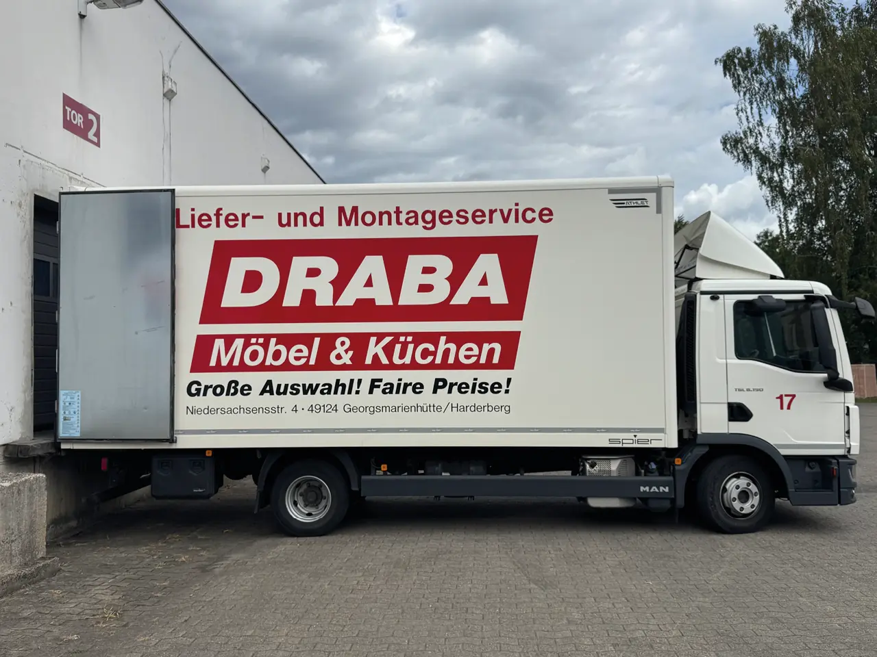 Lieferwagen mit Text DRABA Möbel und Küchen sowie Liefer und Montageservice vor Gebäude